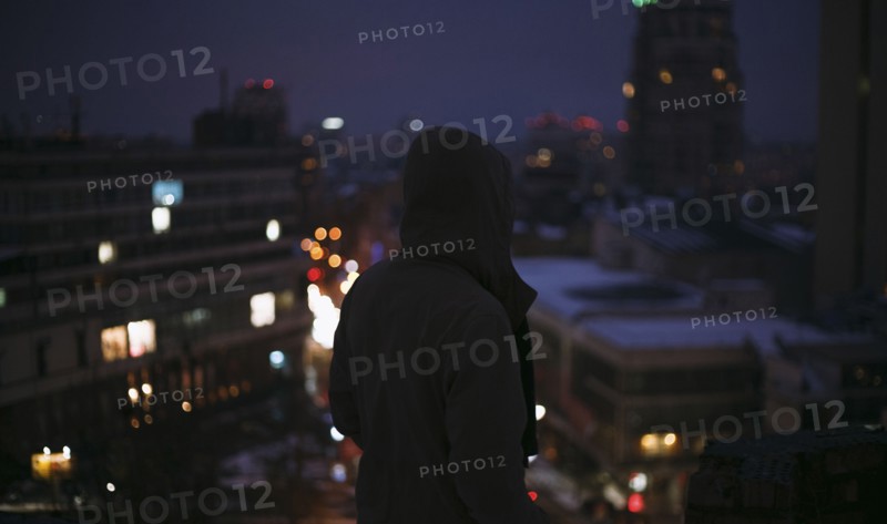 Silhouette of man on roof in city at night