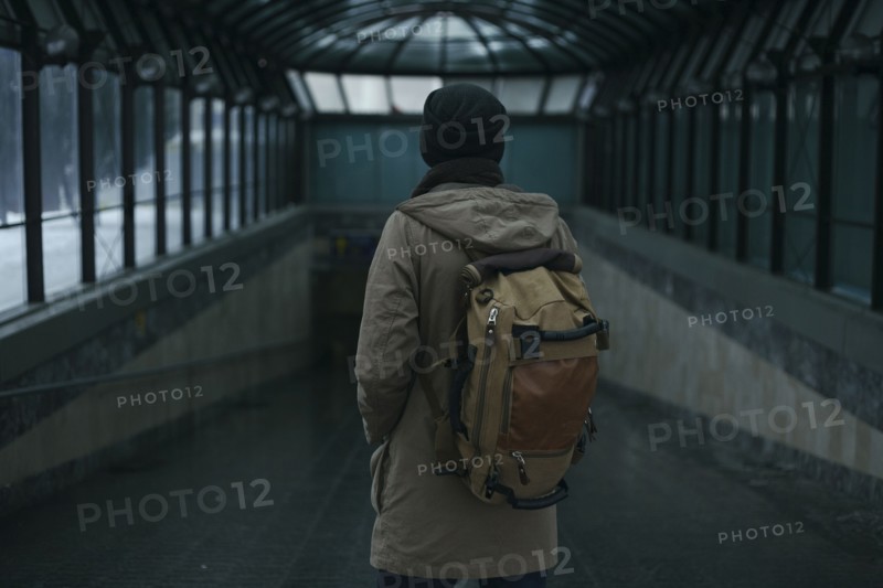 Man standing in tunnel carrying backpack