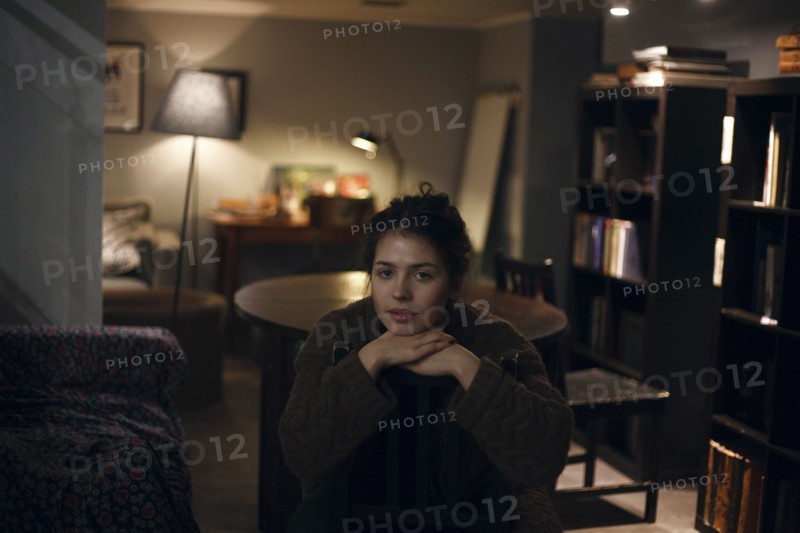 Portrait of smiling Caucasian woman sitting in livingroom at night