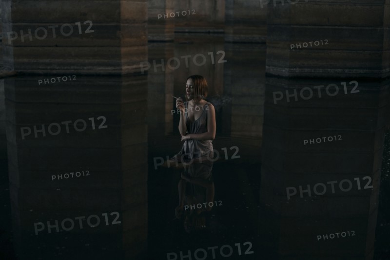 Caucasian woman standing waist deep in water smoking cigarette