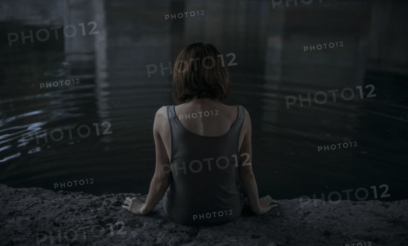 Caucasian woman sitting at edge of water