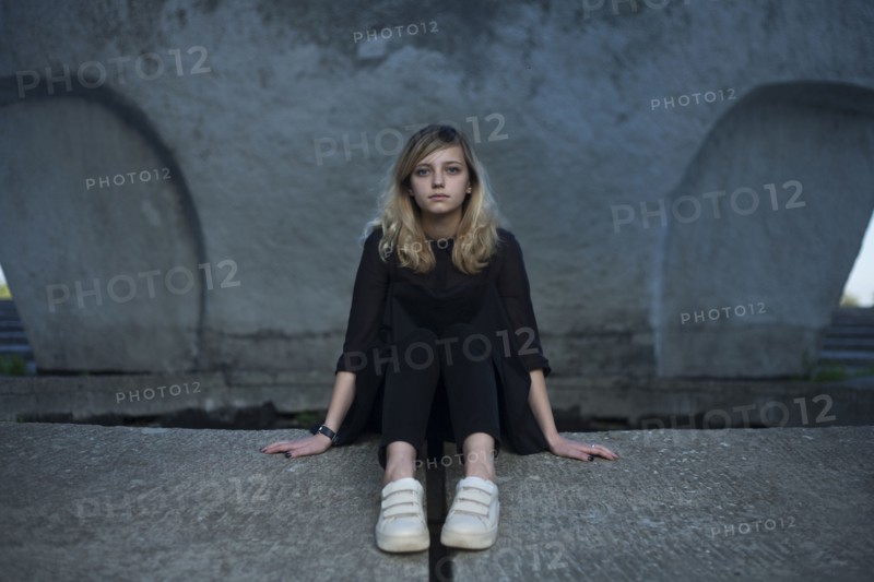 Portrait of serious Caucasian woman sitting on concrete