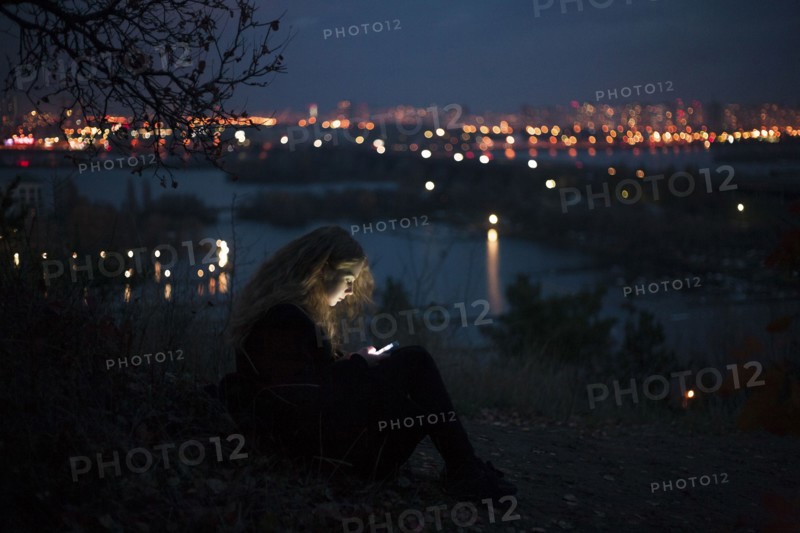 Caucasian woman standing near urban waterfront at night
