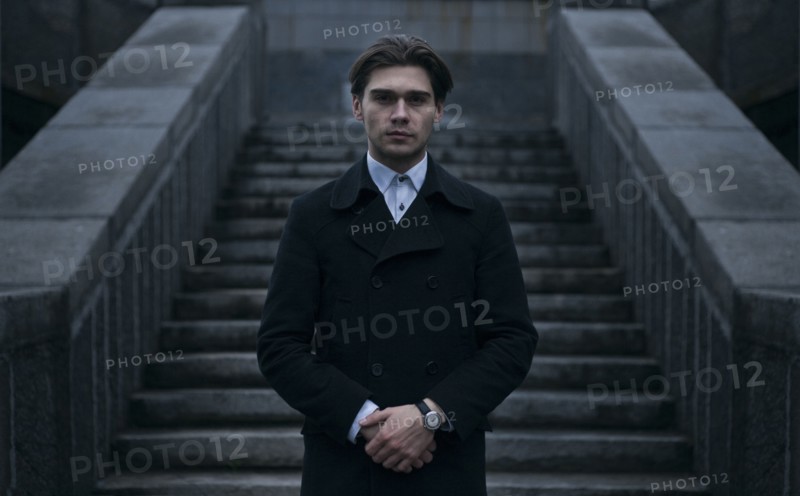 Portrait of serious Caucasian man standing near staircase