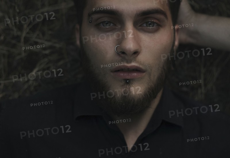 Serious Caucasian man with eyebrow and nose piercing