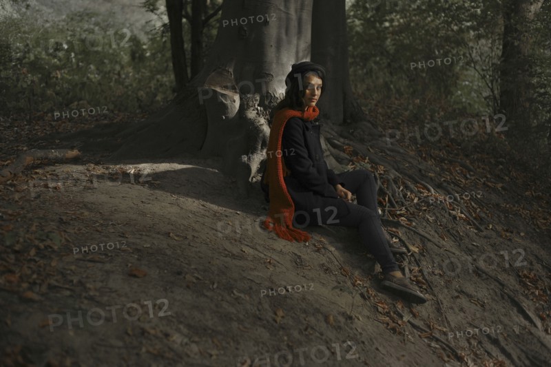 Portrait of Caucasian woman sitting on tree roots in forest