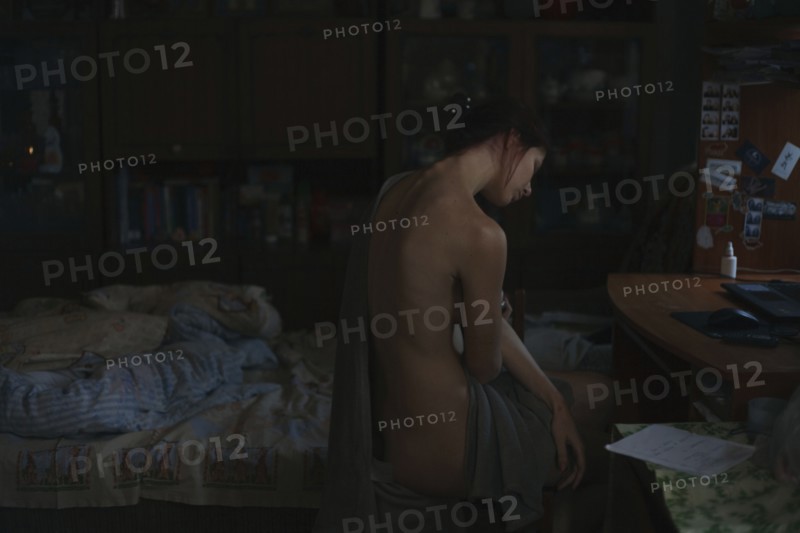 Portrait of naked woman sitting on bed