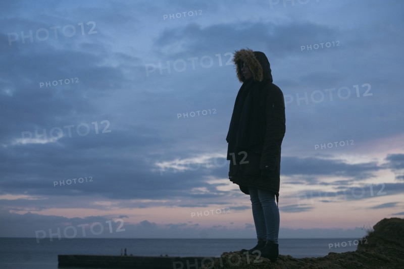 Caucasian woman wearing fur hood at ocean
