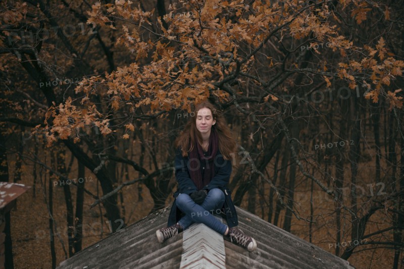 Caucasian woman sitting on roof in autumn