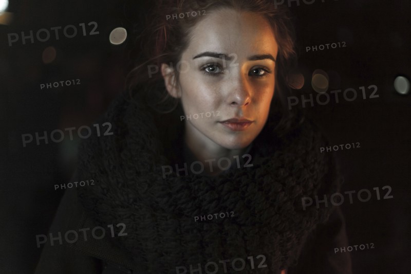Portrait of serious Caucasian woman wearing scarf at night