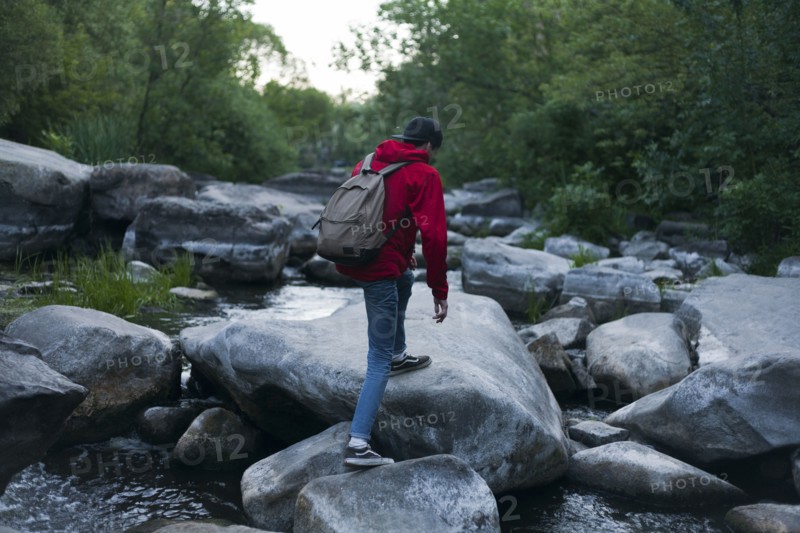 Caucasian man hiking on rocks in river