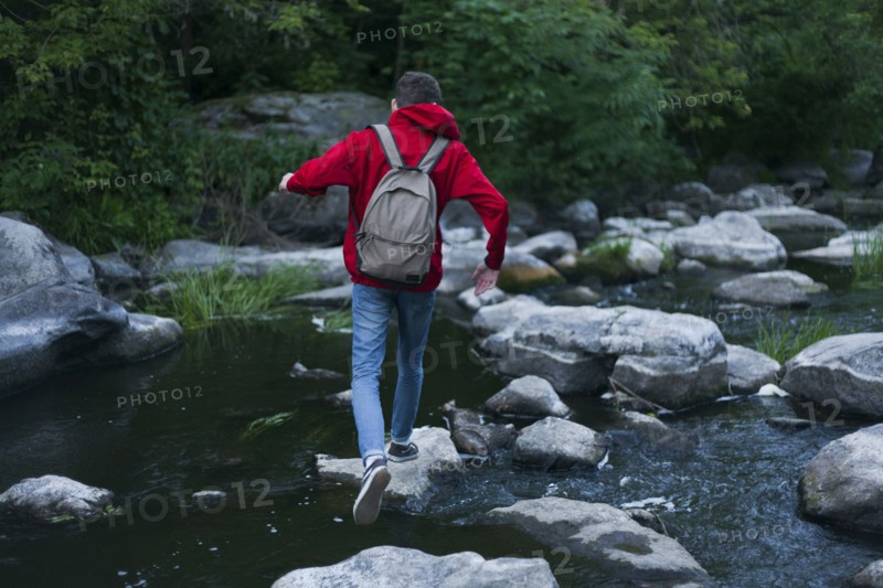 Caucasian man walking on rocks crossing river
