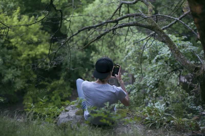 Caucasian man texting on cell phone in woods