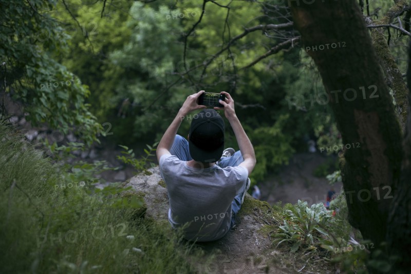 Caucasian man photographing with cell phone in woods