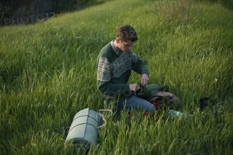 Caucasian hiker kneeling in grass