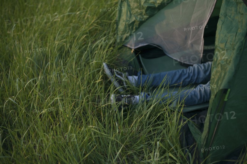 Legs of Caucasian man laying in tent
