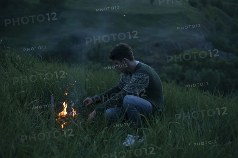 Caucasian man starting campfire at night