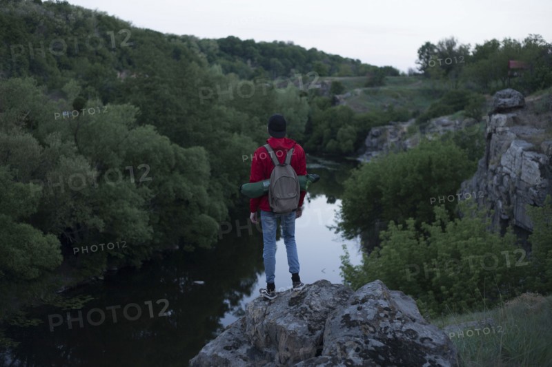 Caucasian hiker standing on rock near river