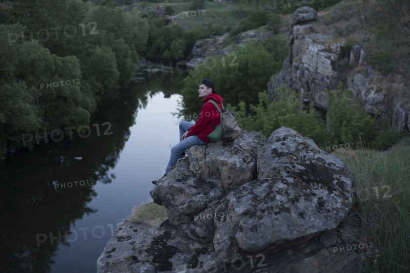 Caucasian man sitting on a rock near river