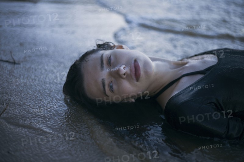 Caucasian woman laying on beach in waves