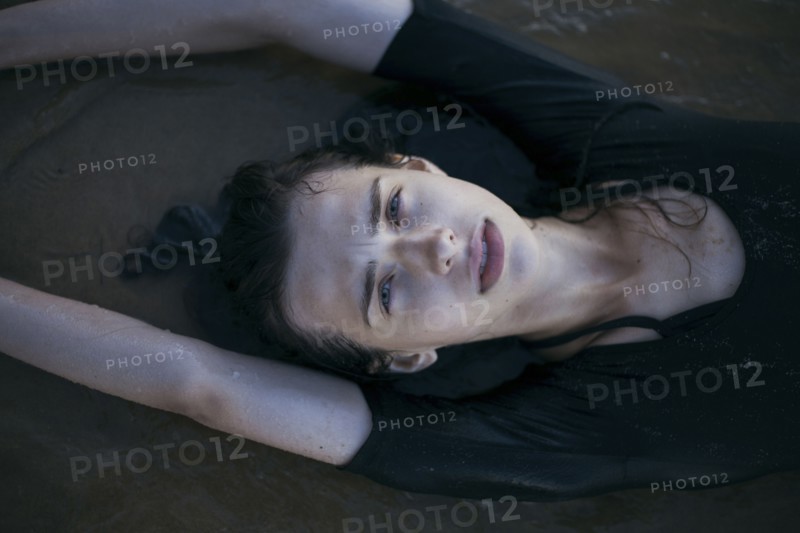 Caucasian woman laying on beach in waves