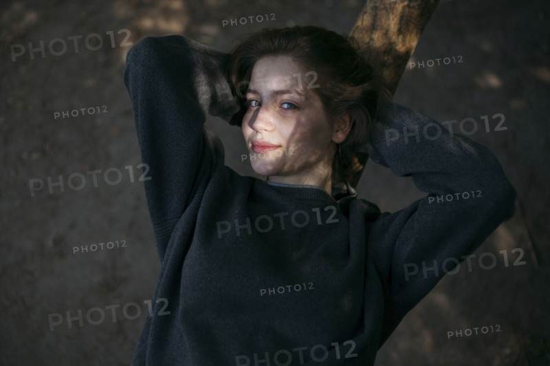 Portrait of smiling Caucasian teenage girl leaning on tree