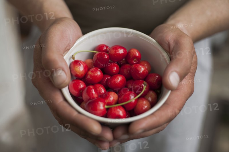 Hands of woman holding a bowl of cherries