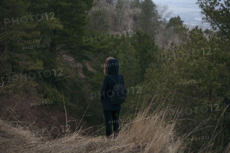 Caucasian woman standing near trees carrying backpack