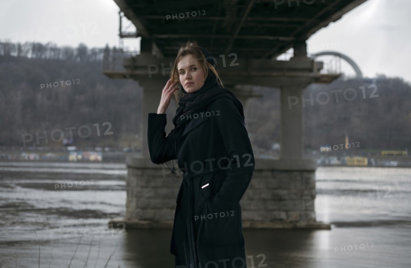 Caucasian woman standing under bridge near river