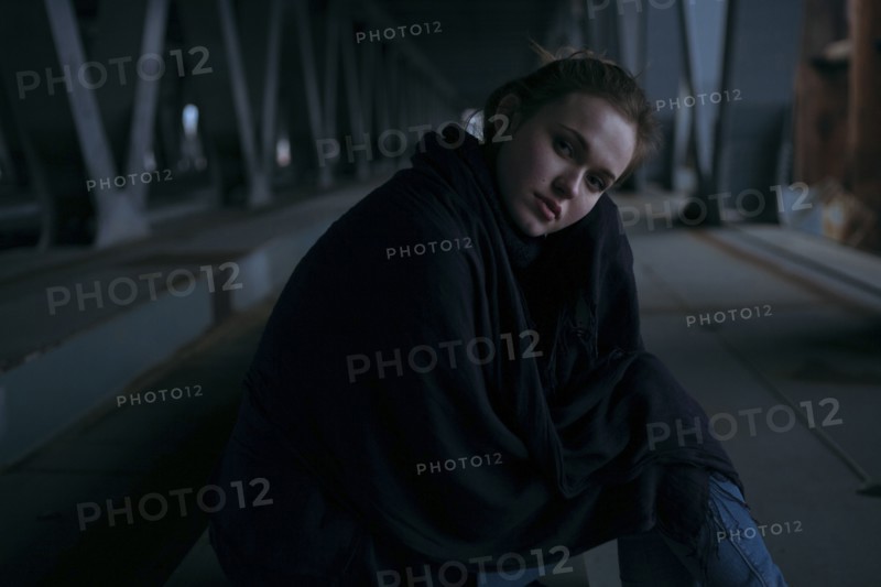 Caucasian woman sitting under bridge