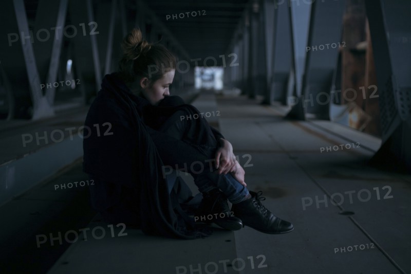 Caucasian woman sitting under bridge