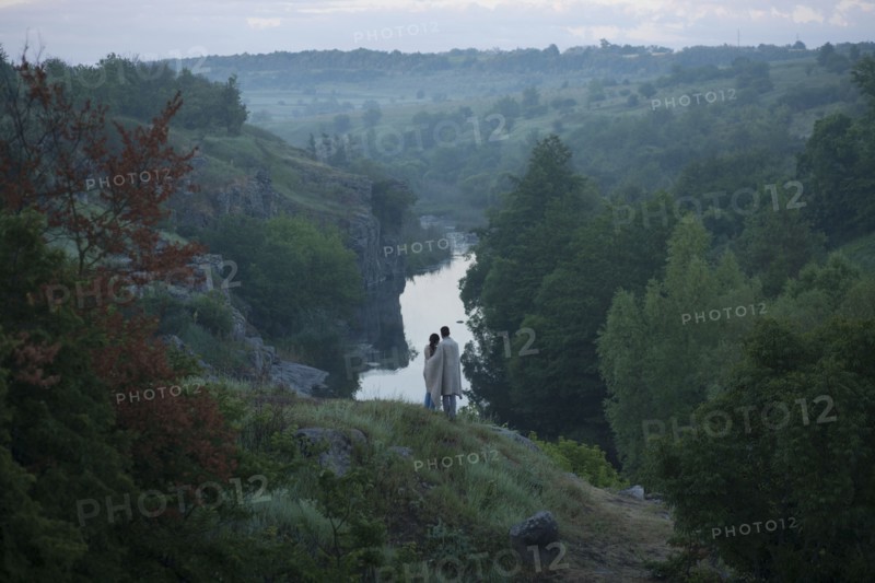Caucasian couple standing on hill admiring river
