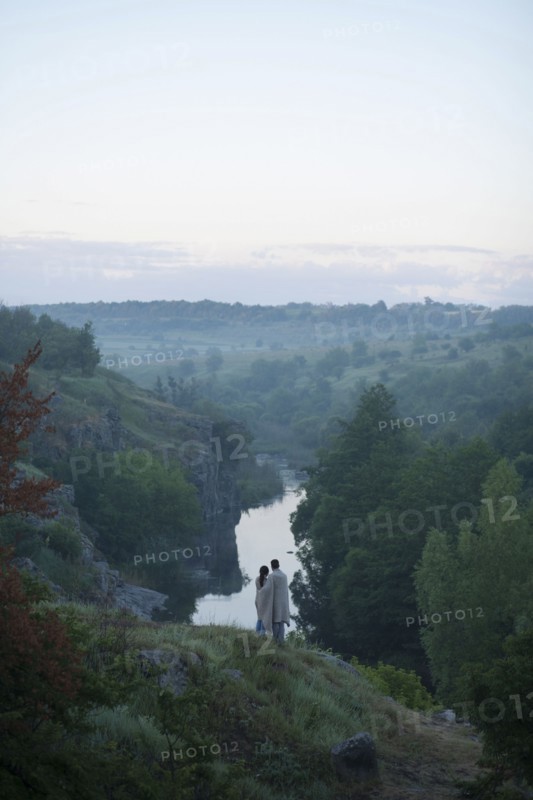 Caucasian couple standing on hill admiring river