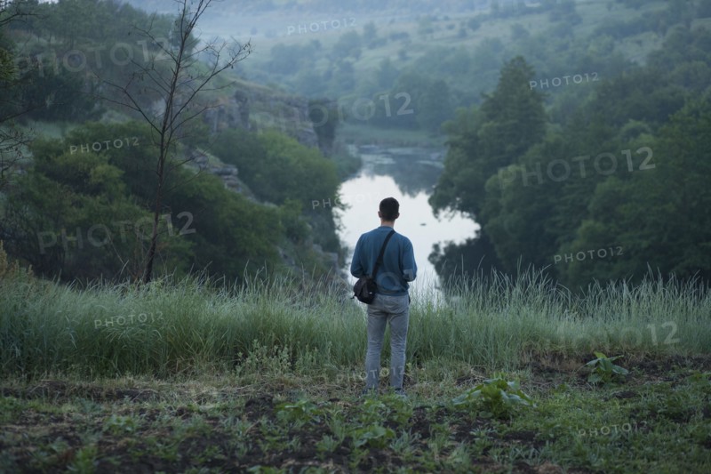 Caucasian man standing on hill above river