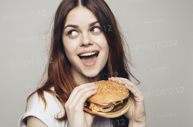 Surprised Caucasian woman holding cheeseburger