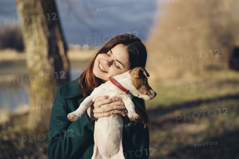 Caucasian woman lifting an hugging dog