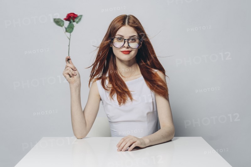 Caucasian woman sitting at windy table holding rose