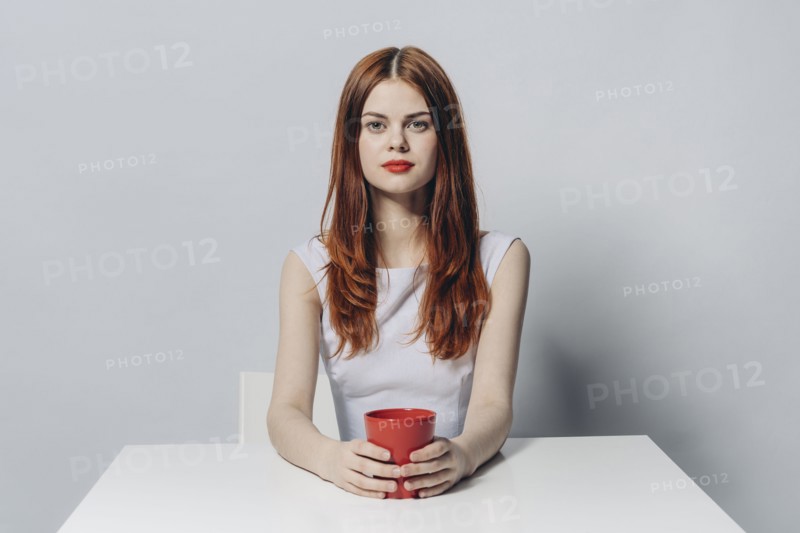 Caucasian woman sitting at table holding red cup