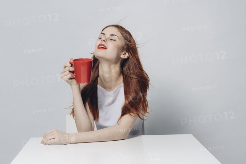 Caucasian woman sitting at windy table holding red cup