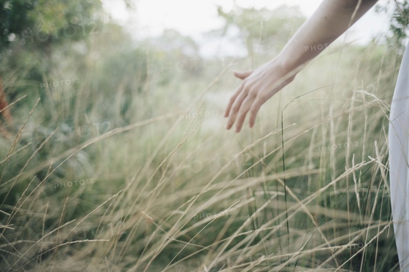 Hand of Caucasian woman standing in tall grass