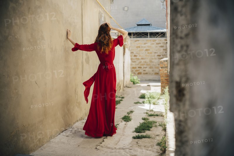 Caucasian woman wearing red dress in alley