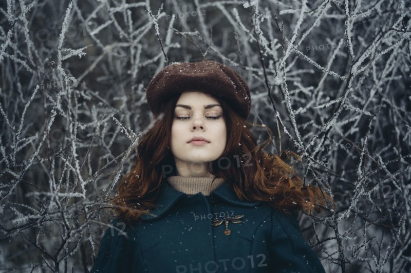 Caucasian woman with eyes closed near icy branches