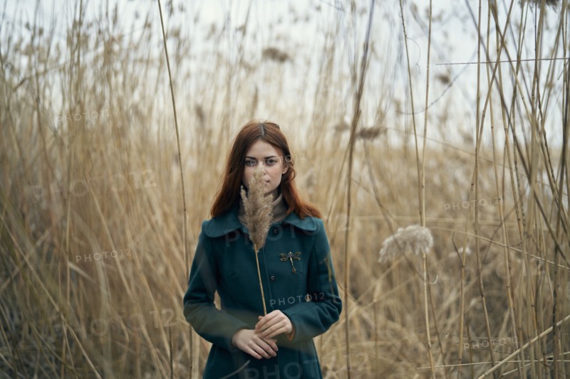 Caucasian woman standing in field holding stalk of grass