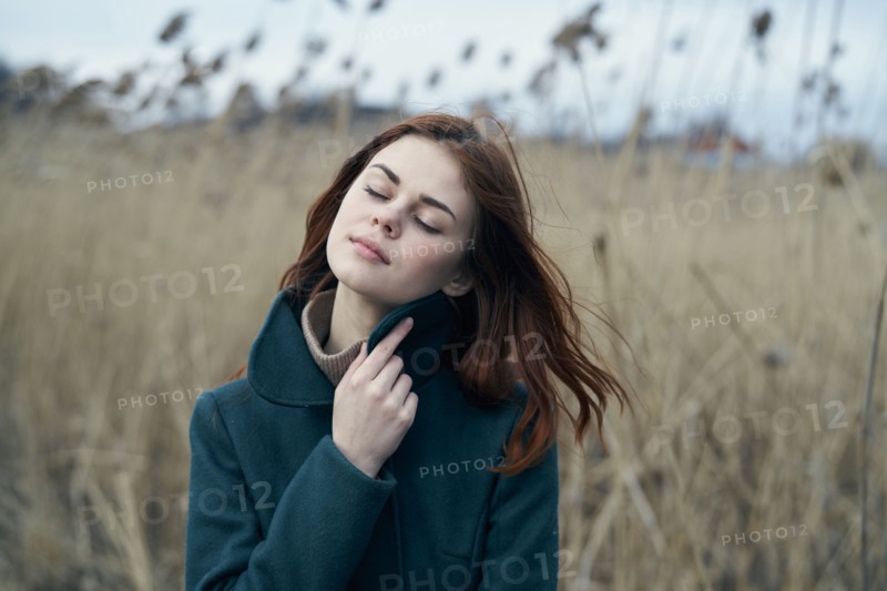 Pensive Caucasian woman standing in field holding collar