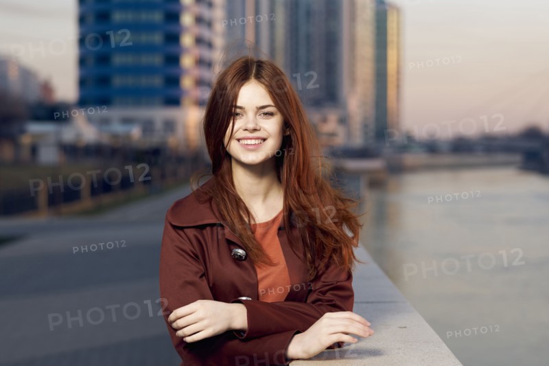 Smiling Caucasian woman leaning on wall at waterfront