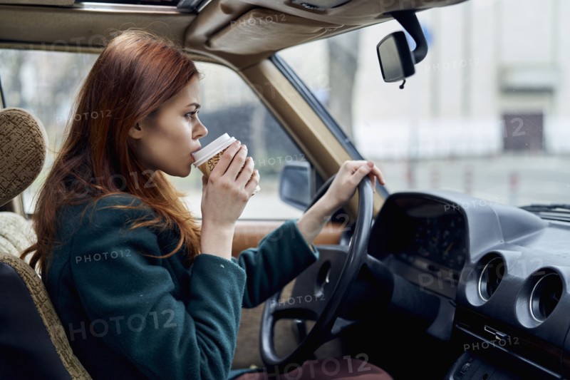 Caucasian woman driving car and drinking coffee