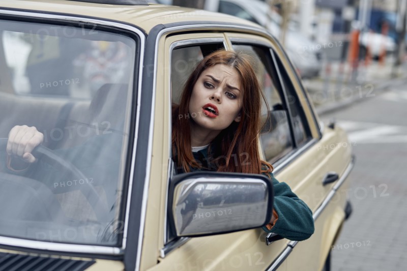 Frustrated Caucasian woman leaning on door driving car