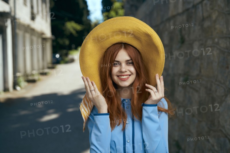 Smiling Caucasian woman wearing hat near stone wall