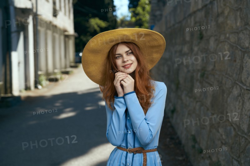 Pensive Caucasian woman wearing hat near stone wall