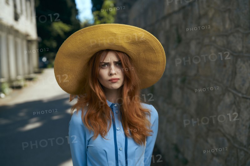 Frustrated Caucasian woman wearing hat near stone wall